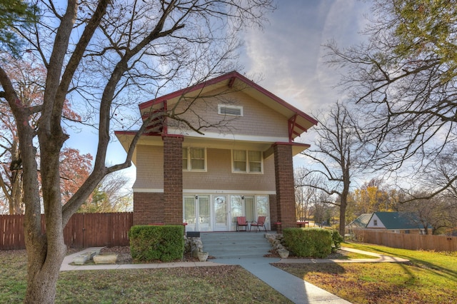 view of front of property with covered porch, fence, and a front yard