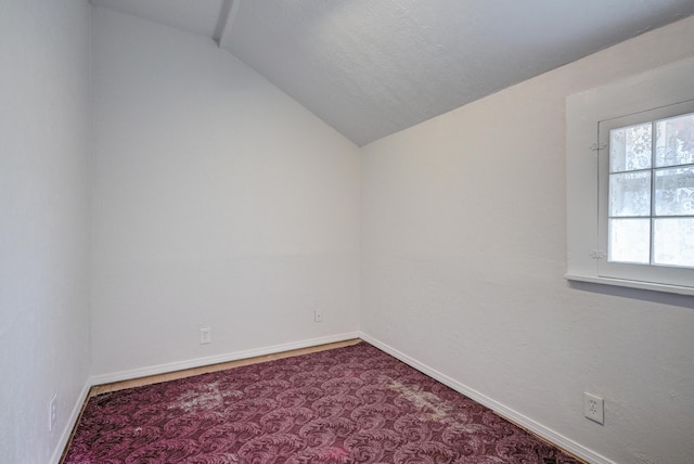 empty room with carpet flooring, baseboards, and lofted ceiling