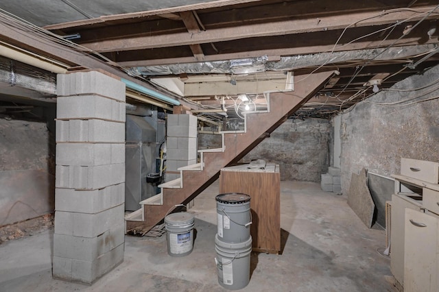unfinished basement featuring heating unit and stairs