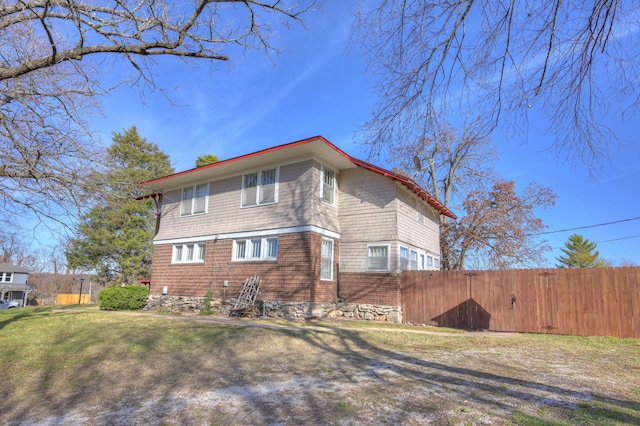 view of side of home with fence and a yard