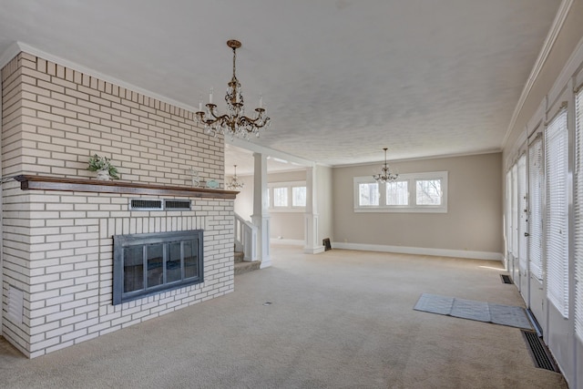 unfurnished living room featuring visible vents, a brick fireplace, ornamental molding, an inviting chandelier, and light colored carpet