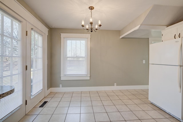 unfurnished dining area featuring baseboards, visible vents, light tile patterned floors, and a chandelier