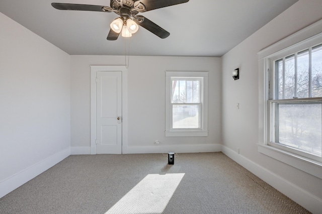 carpeted empty room with baseboards, a wealth of natural light, and a ceiling fan