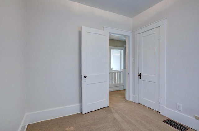 empty room featuring light carpet, baseboards, and visible vents