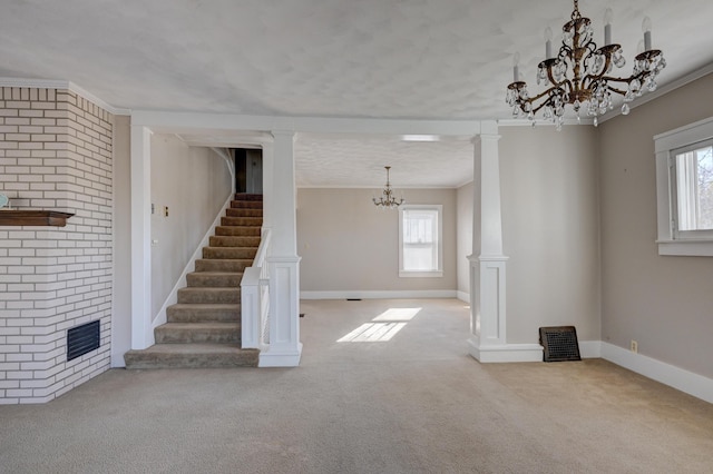 unfurnished living room featuring ornate columns, crown molding, carpet floors, and an inviting chandelier