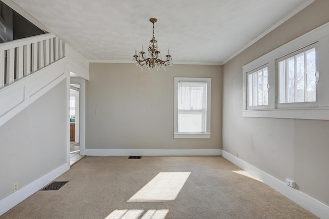 spare room featuring carpet floors, ornamental molding, a chandelier, and visible vents