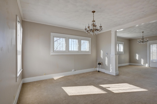carpeted empty room with baseboards, a notable chandelier, ornamental molding, and ornate columns