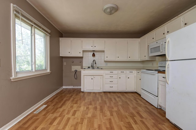 kitchen with white cabinetry, light wood finished floors, a sink, and white appliances