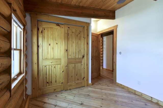interior space with hardwood / wood-style flooring, beam ceiling, multiple windows, and rustic walls