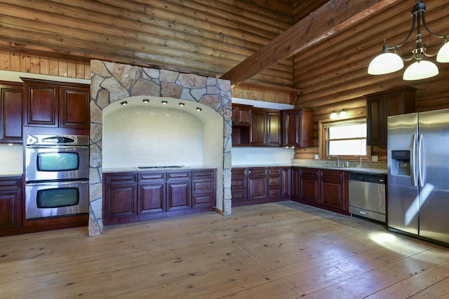 kitchen featuring light countertops, rustic walls, stainless steel appliances, a sink, and light wood finished floors