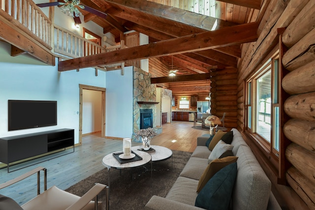 living room with high vaulted ceiling, hardwood / wood-style flooring, a stone fireplace, beamed ceiling, and ceiling fan