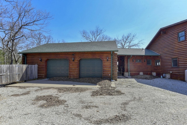 view of front of property with fence, log siding, an attached garage, and roof with shingles