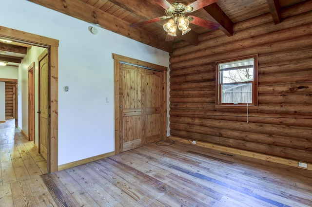 unfurnished bedroom with beamed ceiling, light wood-style floors, rustic walls, and wood ceiling