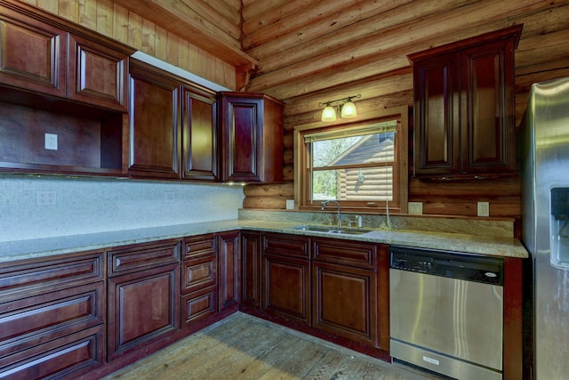 kitchen featuring a sink, light stone countertops, log walls, stainless steel appliances, and light wood-style floors