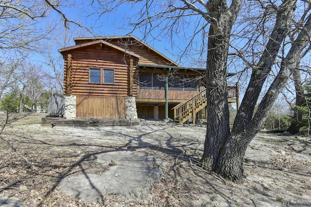 log-style house with a sunroom, stairs, and log exterior
