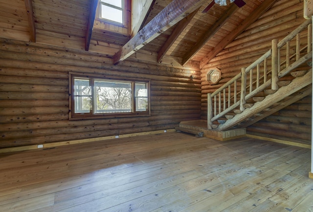 empty room featuring beamed ceiling, stairs, rustic walls, hardwood / wood-style floors, and wood ceiling