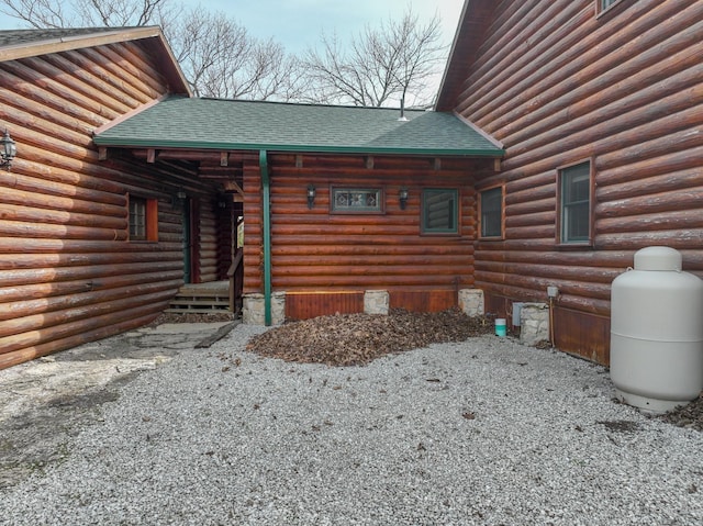 view of side of home featuring log siding and roof with shingles