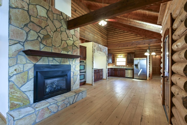 unfurnished living room featuring high vaulted ceiling, beam ceiling, a stone fireplace, rustic walls, and light wood-style floors