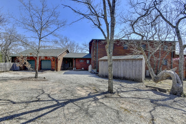 view of front of house with log siding, driveway, fence, and an attached garage