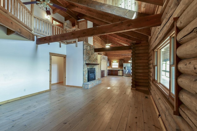 unfurnished living room featuring baseboards, beamed ceiling, light wood-style flooring, and a ceiling fan