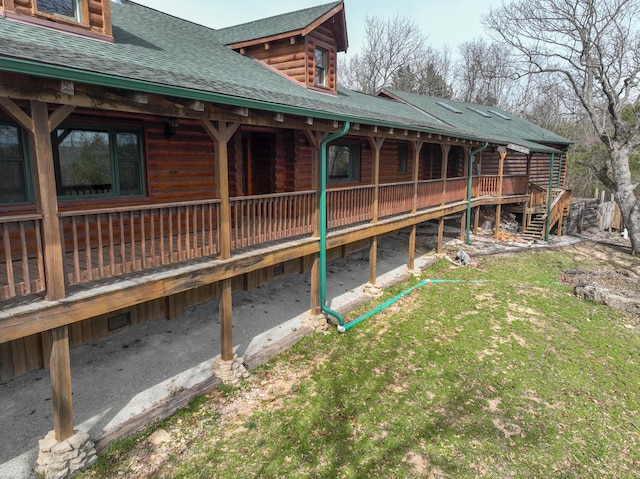 view of side of property featuring a shingled roof and log siding