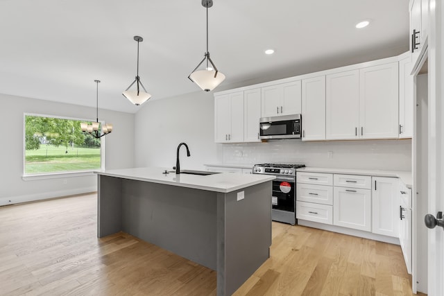 2117 N Silver Charm Ave, Springfield, MO 65802 - kitchen with appliances with stainless steel finishes, light countertops, light wood-style flooring, a kitchen island with sink, and decorative backsplash