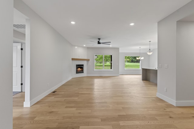 2117 N Silver Charm Ave, Springfield, MO 65802 - unfurnished living room featuring a ceiling fan, light wood finished floors, a fireplace, recessed lighting, and a chandelier