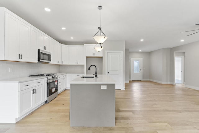 2117 N Silver Charm Ave, Springfield, MO 65802 - kitchen with appliances with stainless steel finishes, light wood-style flooring, light countertops, a center island with sink, and pendant lighting
