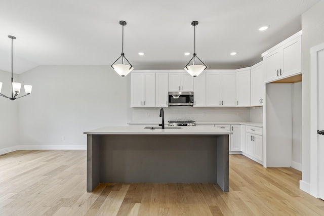 2117 N Silver Charm Ave, Springfield, MO 65802 - kitchen with stainless steel microwave, light countertops, light wood-type flooring, white cabinets, and a center island with sink