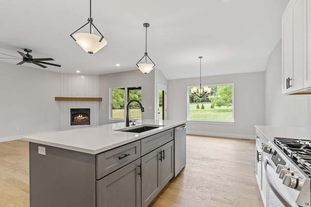 2117 N Silver Charm Ave, Springfield, MO 65802 - kitchen featuring gray cabinetry, a large fireplace, appliances with stainless steel finishes, light countertops, and a kitchen island with sink