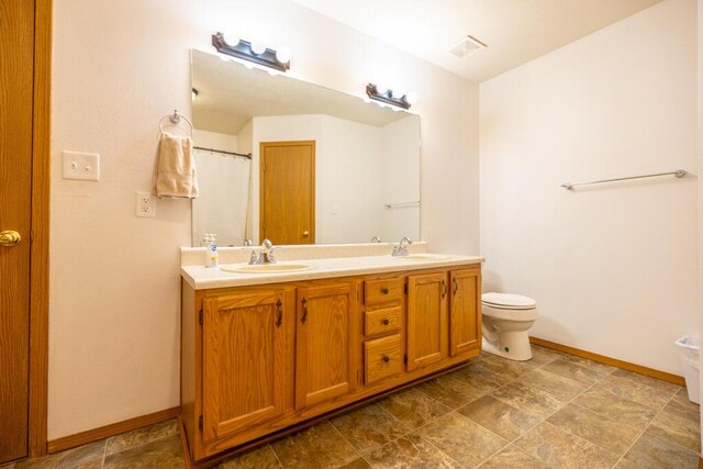 919 S Central Ave, Marionville, MO 65705 - bathroom featuring baseboards, toilet, double vanity, and a sink