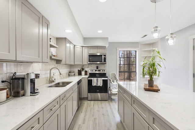 kitchen featuring gray cabinetry, a sink, open shelves, and appliances with stainless steel finishes