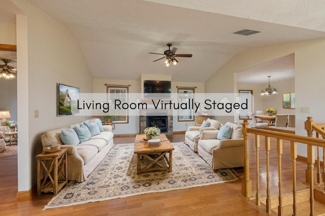 1206 Black Horse Rd, Conway, MO 65632 - living room featuring lofted ceiling, ceiling fan, wood finished floors, a fireplace, and a chandelier