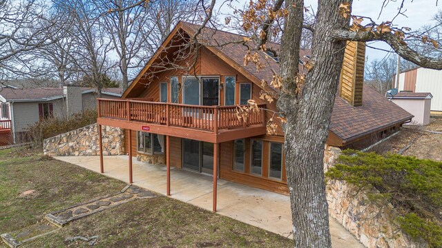 25827 Canyon Dr, Hermitage, MO 65668 - rear view of house with stone siding, a patio, a chimney, a deck, and roof with shingles