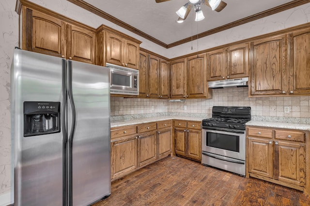 3607 Quail Run Rd, West Plains, MO 65775 - kitchen with appliances with stainless steel finishes, under cabinet range hood, brown cabinetry, ornamental molding, and dark wood-style flooring