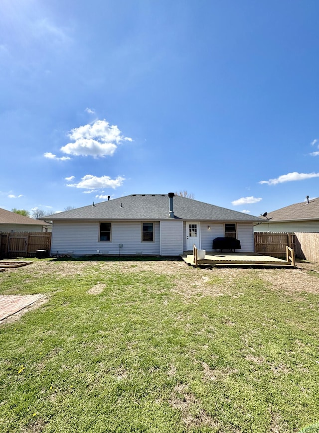 rear view of property featuring fence, a deck, and a lawn