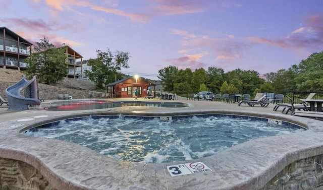 164 Dogwood Park Trl Bldg 1204, Branson, MO 65616 - pool at dusk featuring a community hot tub, fence, a water slide, and a patio