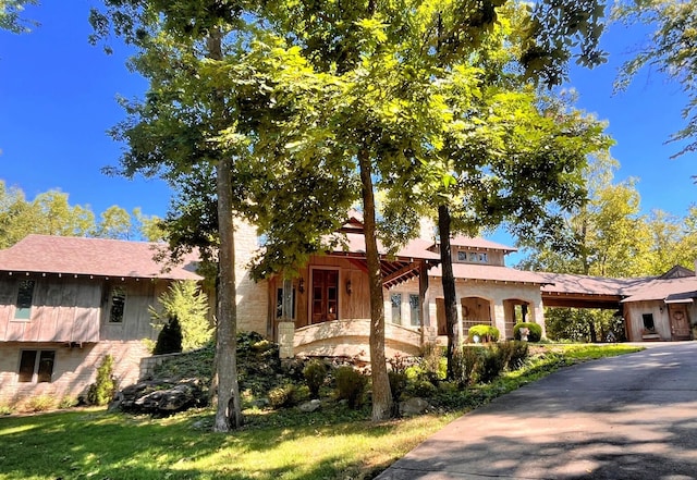 mediterranean / spanish house with stone siding and a front yard