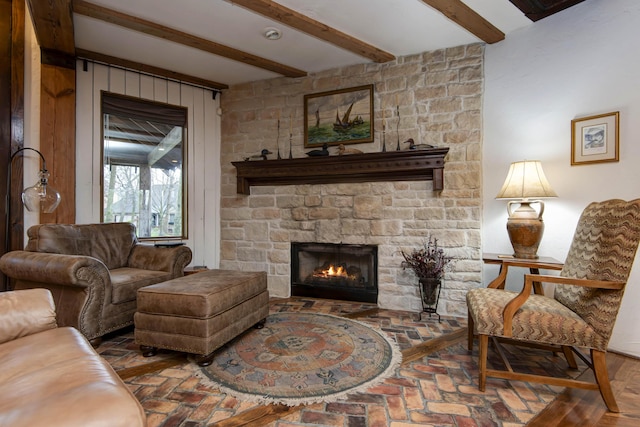 living room with brick floor, beamed ceiling, and a stone fireplace