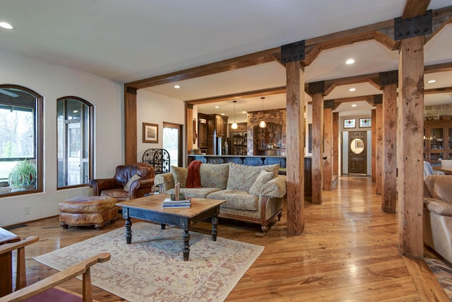 living room with light wood-style flooring, arched walkways, beamed ceiling, and recessed lighting