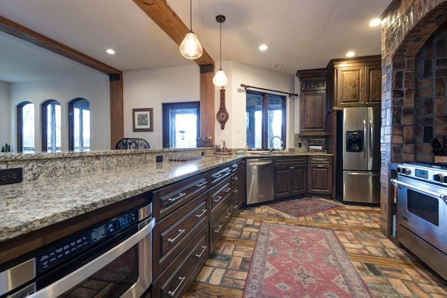 kitchen with a wealth of natural light, appliances with stainless steel finishes, brick floor, and recessed lighting