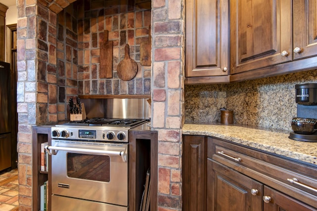 kitchen with light stone counters, high end stainless steel range oven, and backsplash