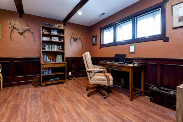 office area featuring a wainscoted wall, visible vents, beamed ceiling, and wood finished floors