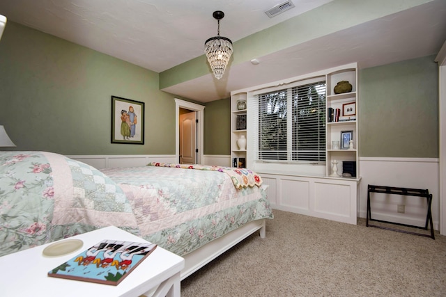 carpeted bedroom featuring visible vents and an inviting chandelier
