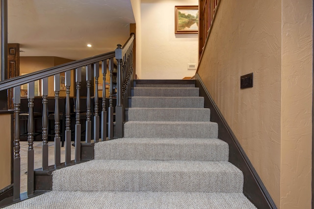 stairs with carpet flooring, a textured wall, and recessed lighting