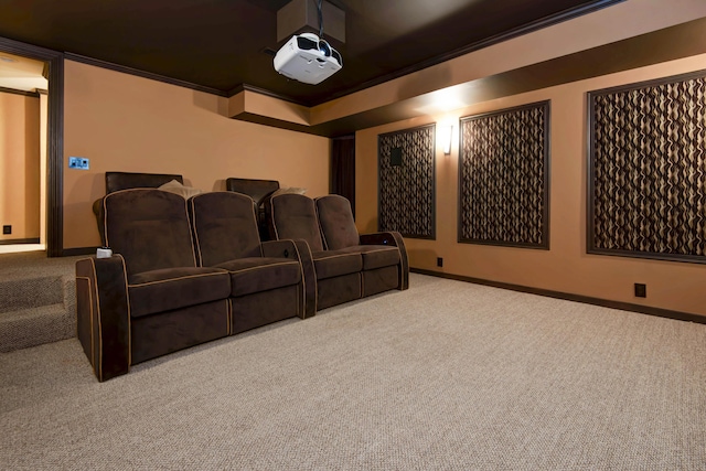 carpeted home theater with crown molding and baseboards