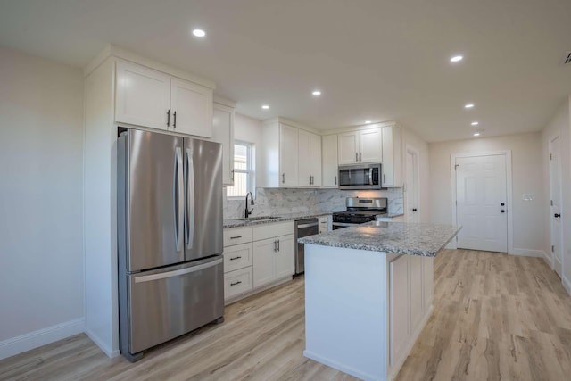 kitchen featuring a sink, white cabinets, appliances with stainless steel finishes, and light stone countertops