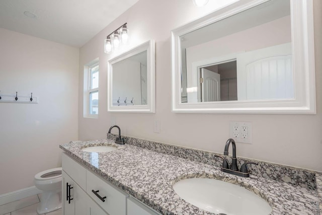full bath featuring toilet, tile patterned floors, double vanity, and a sink