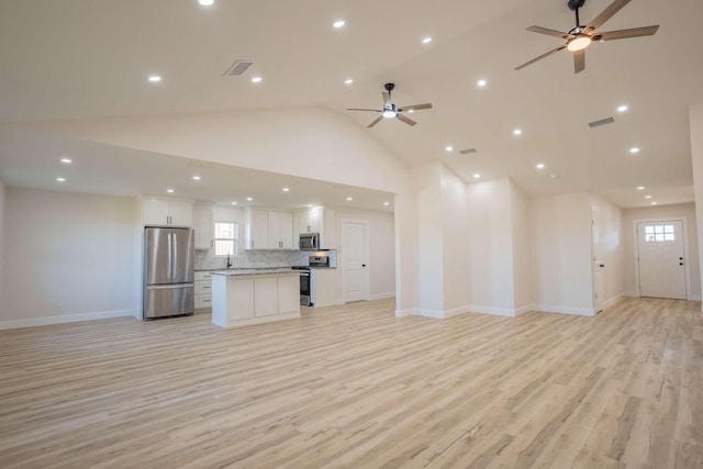 unfurnished living room with light wood finished floors, visible vents, high vaulted ceiling, and ceiling fan