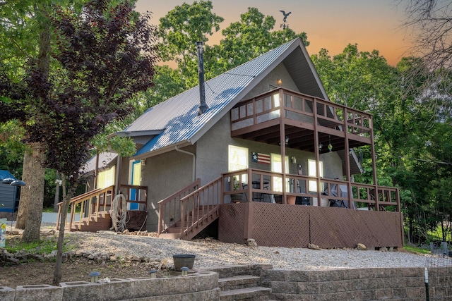 645 Buck Run Dr, Branson West, MO 65737 - back of house at dusk with stucco siding, stairway, and metal roof